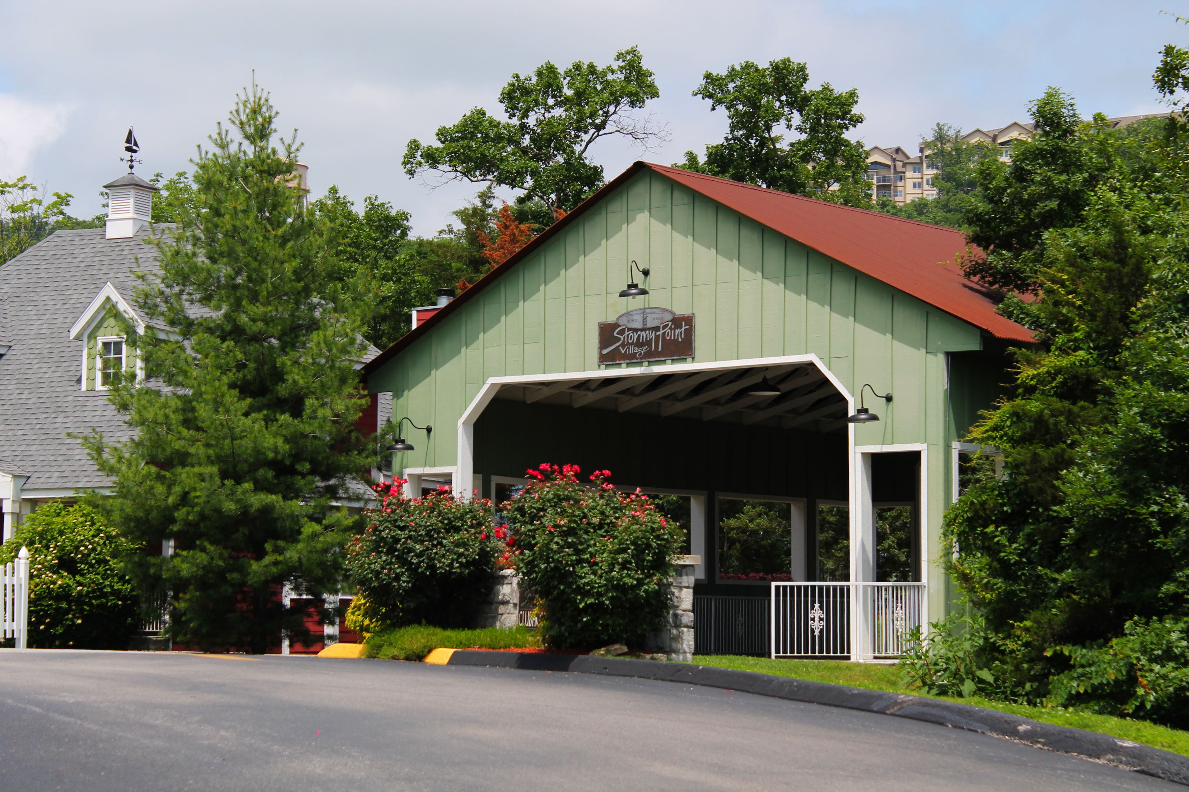 A green building with a red roof, a sign reading "Stormy Point Village Inn," and a covered porch.