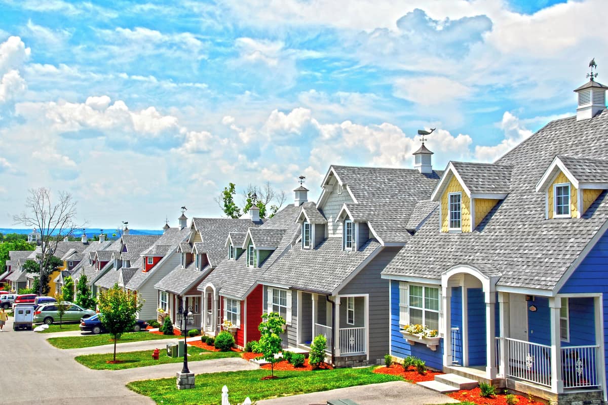 A row of townhouses with grey roofs, red and blue accents, and a clear sky.