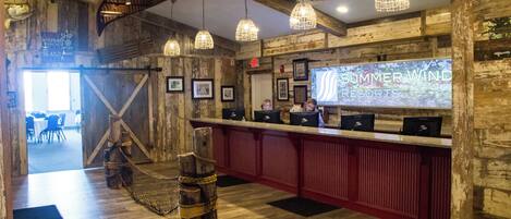 A rustic interior with wooden walls, a reception desk, and hanging pendant lights.