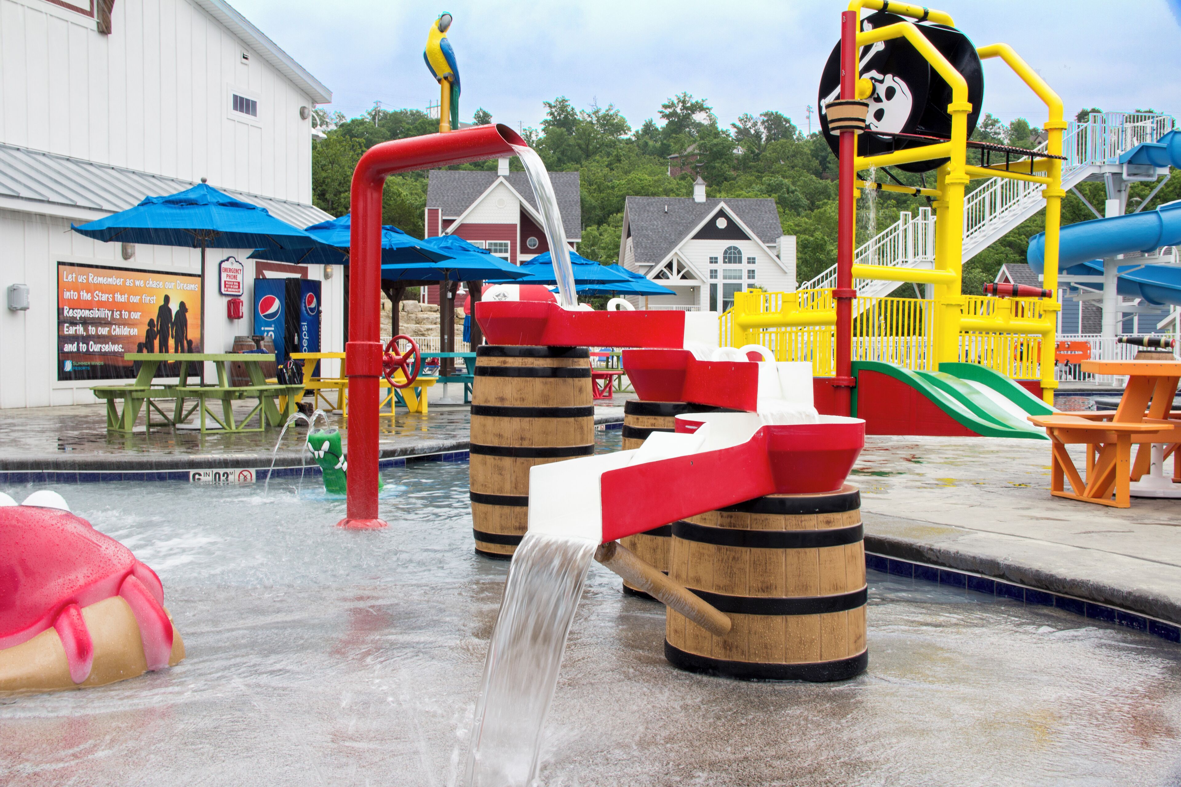 Un espacio de juegos acuáticos con un tobogán, una bomba de agua y una piscina.