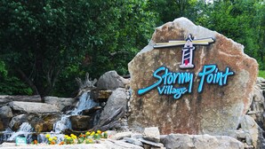 A large rock with the text "Stormy Point Village" and a lighthouse graphic.