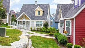 A residential neighborhood with houses featuring gabled roofs, front porches, and a stone pathway leading to the entrance.