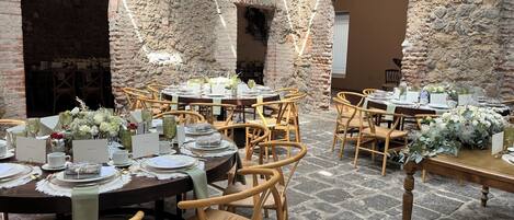 Un comedor rústico con paredes de piedra y mesas de madera preparadas para una comida.