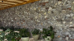 A spa area with a stone wall, a wooden ceiling, and a rectangular hot tub. - Hotel Boutique Casareyna (Puebla)