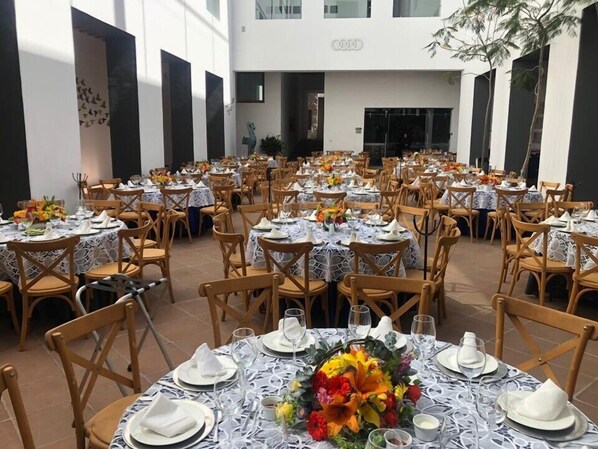 Un amplio comedor interior con mesas redondas, manteles blancos y sillas de madera.