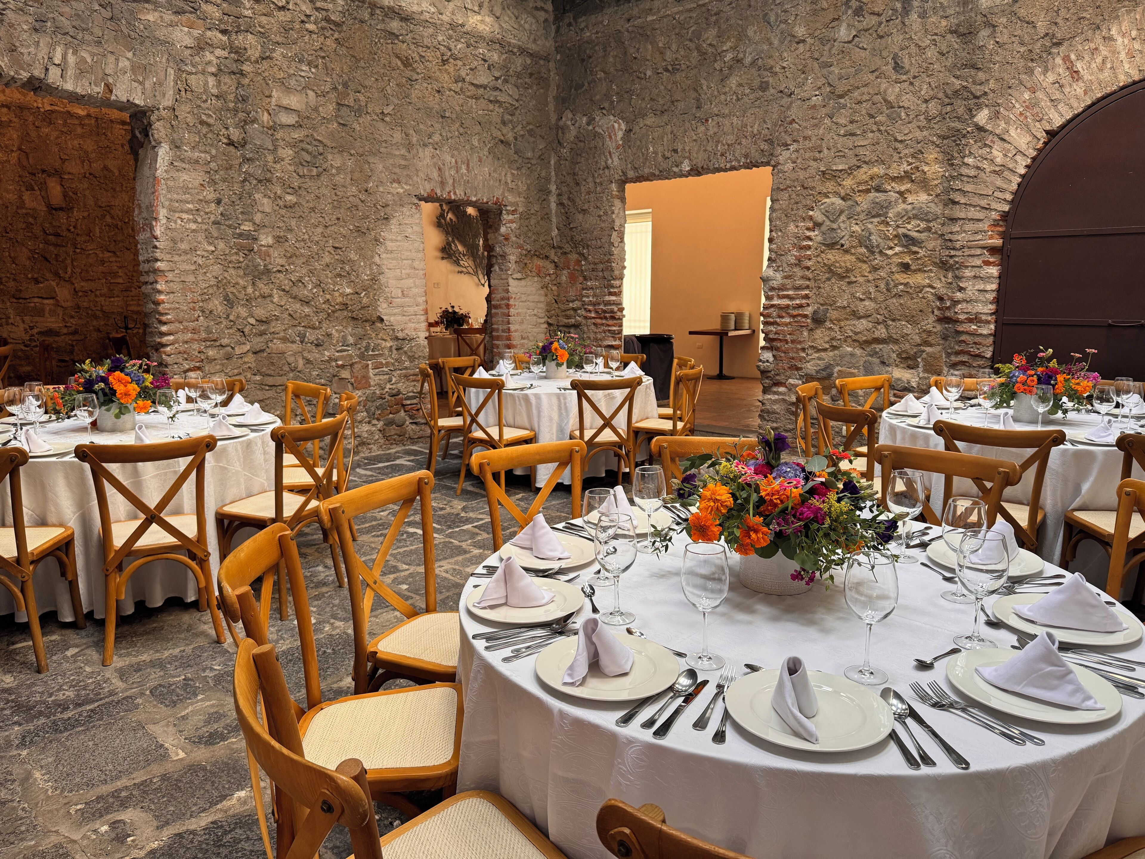 Un restaurant amb taules rodones, cobertes amb teles blanques, caires de fusta i centrals florals.