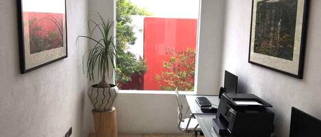 A modern office space with a desk, computer, printer, and a potted plant.
