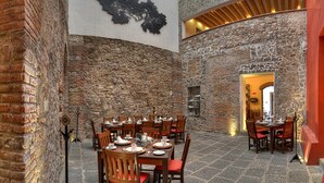 A restaurant with stone walls and wooden tables and chairs. - Hotel Boutique Casareyna (Puebla)