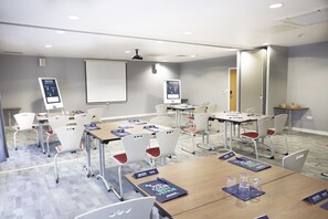 Host meetings and presentations in a well-equipped space with tables, nameplates, and a large whiteboard.