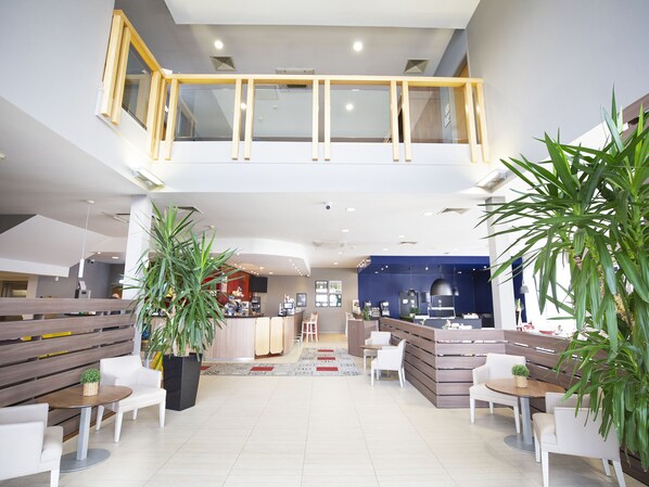 Welcome to our hotel lobby, featuring a central reception desk, comfortable seating areas, and lush greenery.