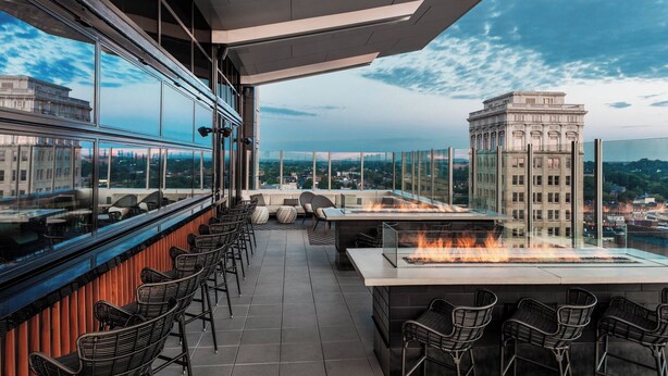 Un bar en la azotea con una chimenea, asientos y vistas panorámicas de la ciudad.