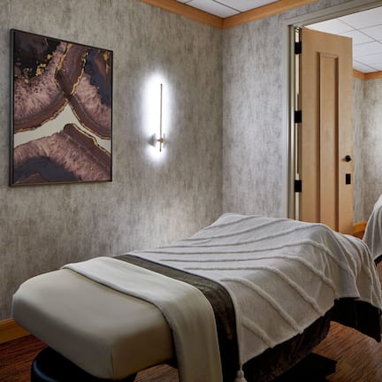 A room with two beds, a painting on the wall, and a door leading to a bathroom.