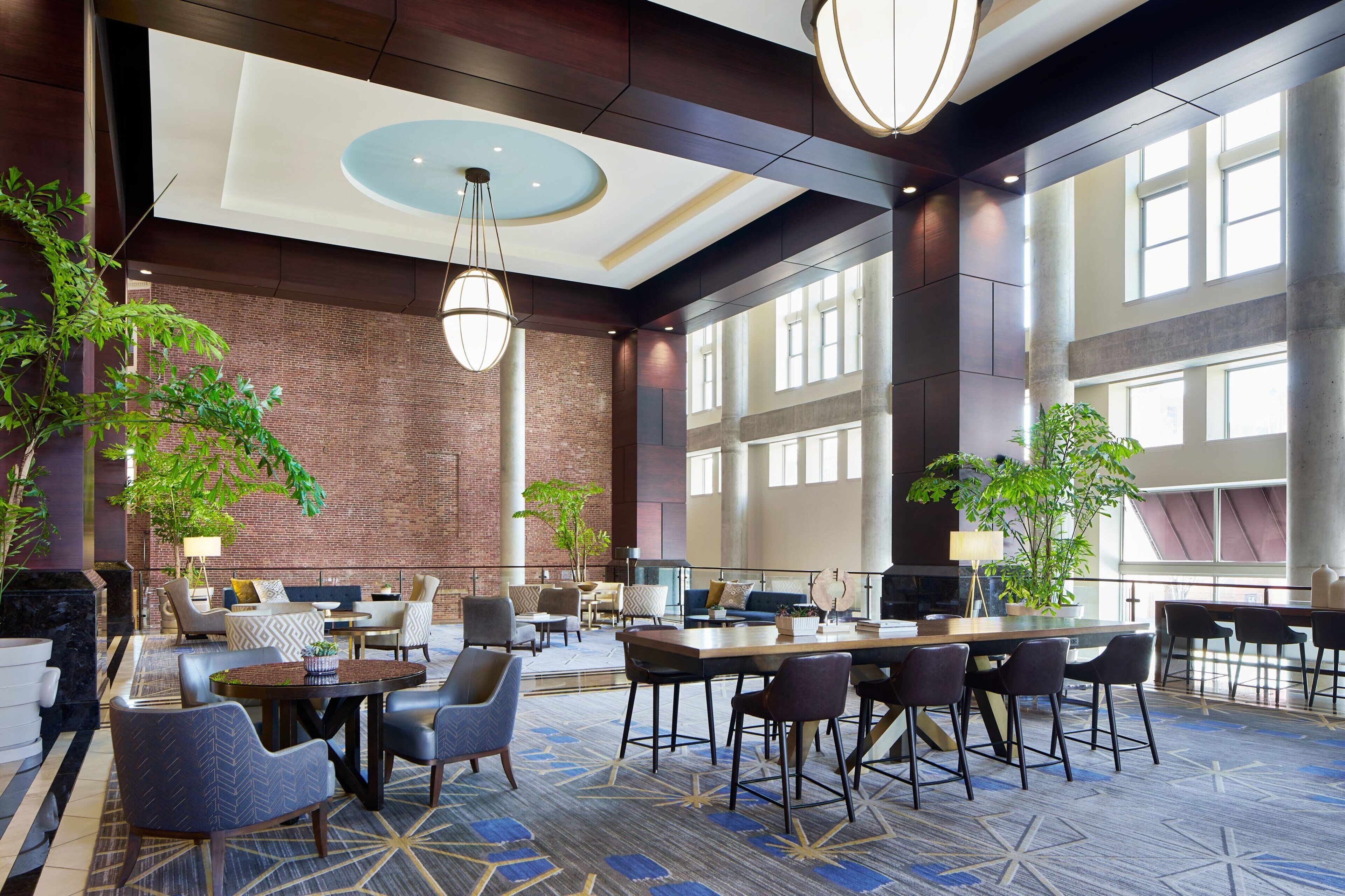 A spacious lobby with a high ceiling, large windows, and a mix of seating areas including sofas and chairs.