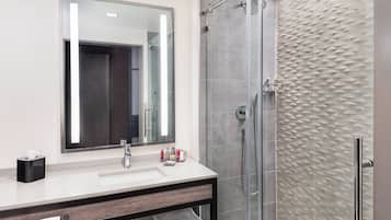 A modern bathroom with a large mirror, a sink, a shower, and a towel rack.