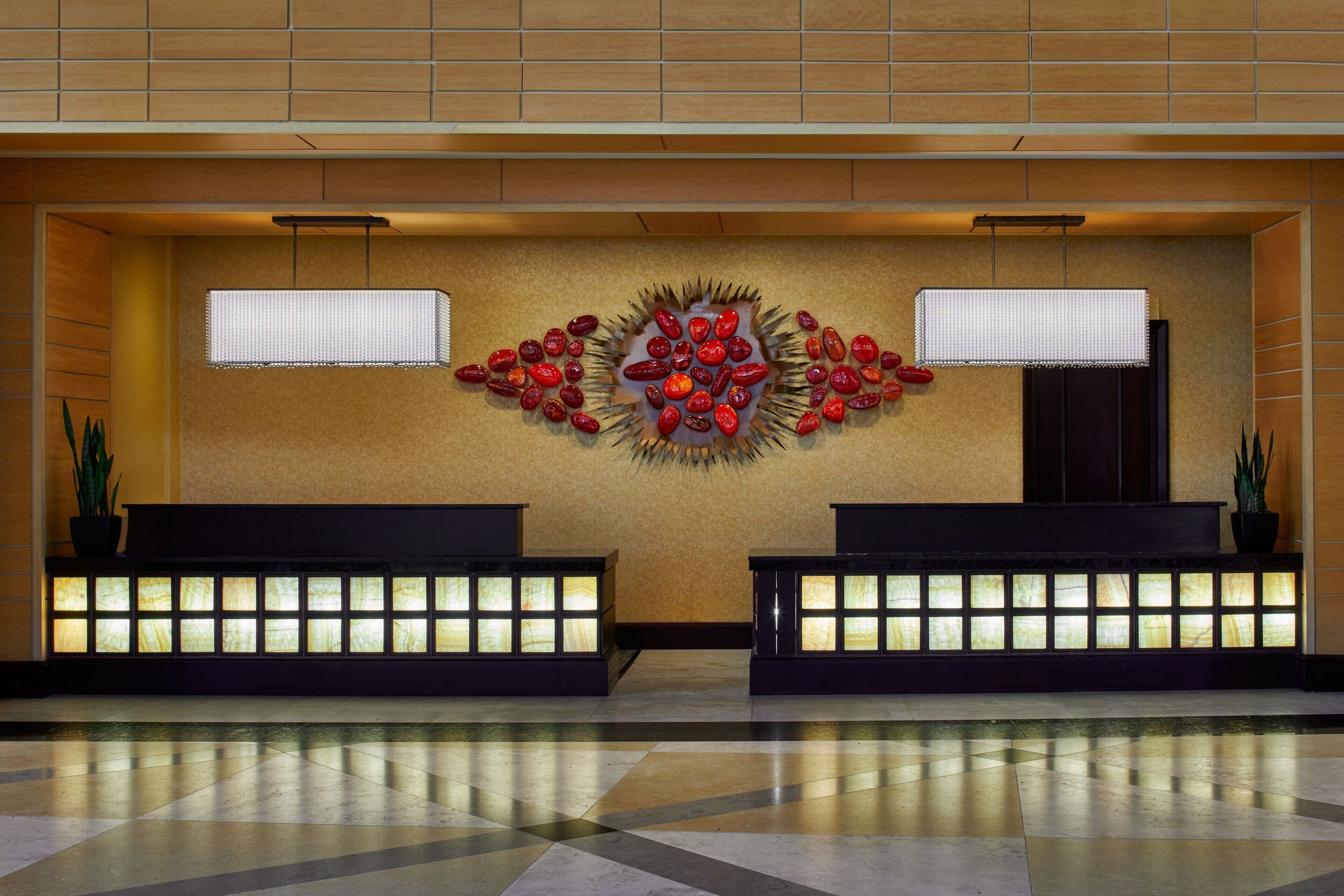 A reception area with a modern design, featuring a central decorative wall and two illuminated reception desks.