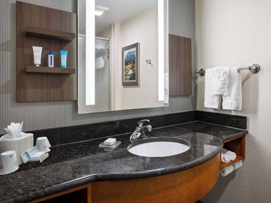 A bathroom with a large mirror, a sink, and a towel rack.