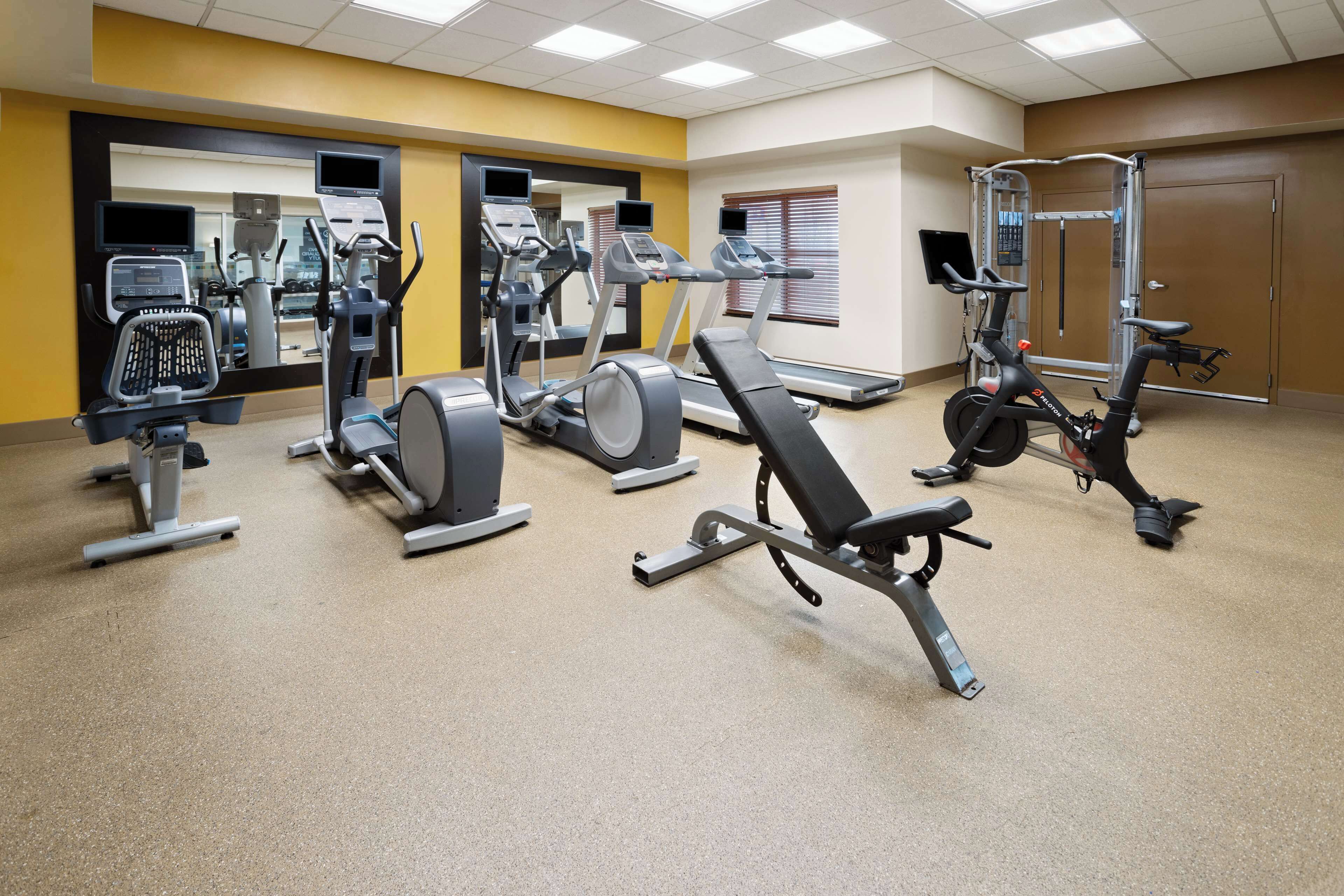 A gym with various exercise equipment including treadmills, elliptical machines, and weight machines.