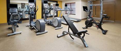 A gym with various exercise equipment including treadmills, elliptical machines, and weight machines.