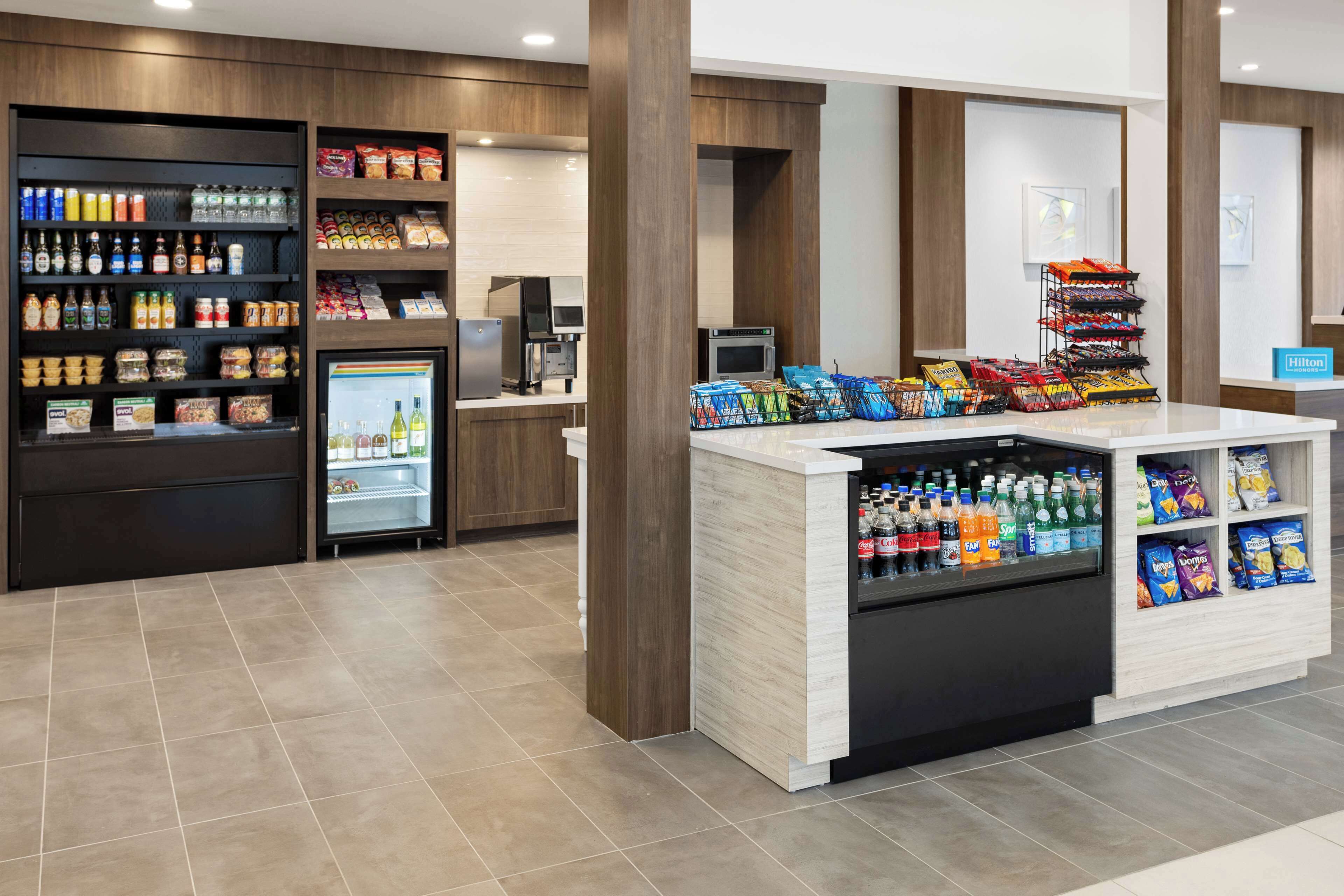 A self-service beverage and snack station with refrigerated drinks, a coffee machine, and various snack options.