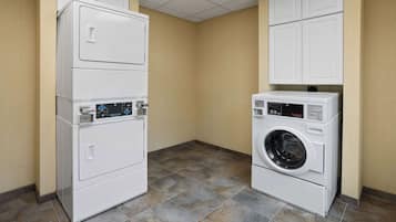 A laundry room with stacked washer and dryer units, beige walls, and tiled flooring.
