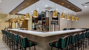 A bar area with a long counter, multiple bar stools, and hanging pendant lights. - Hilton Garden Inn Tifton (Tifton)