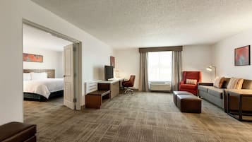 A hotel room with a bed, desk, chair, sofa, and ottoman.