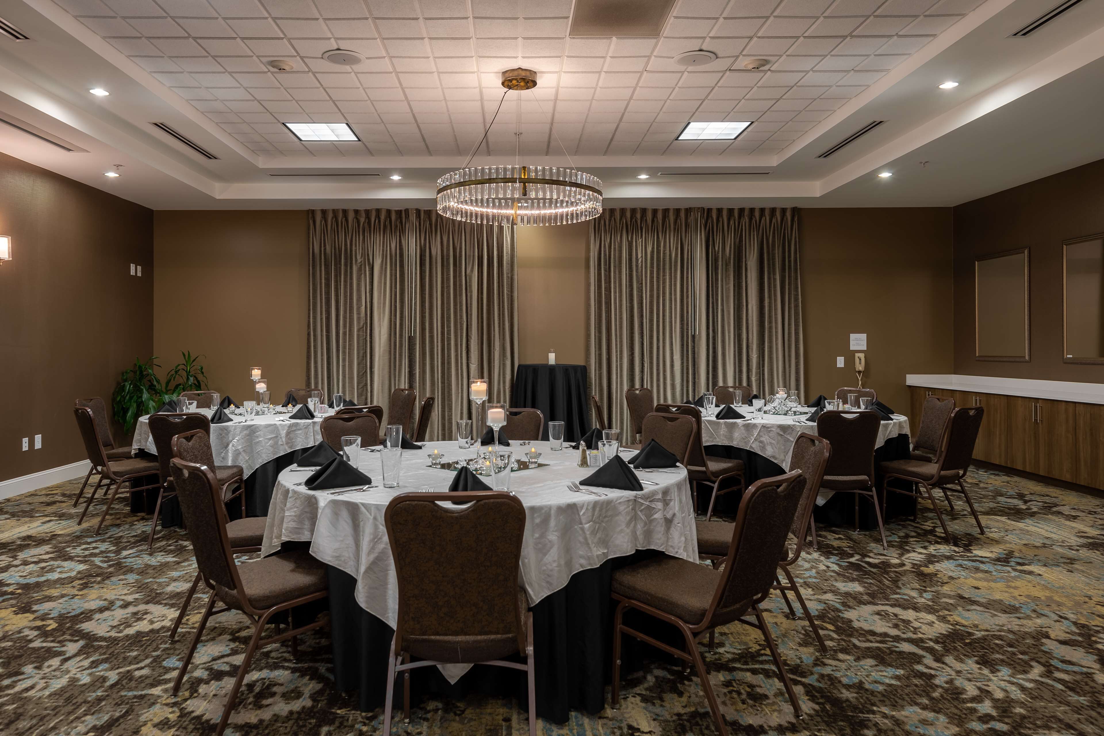 A conference room with round tables, chairs, and a chandelier.