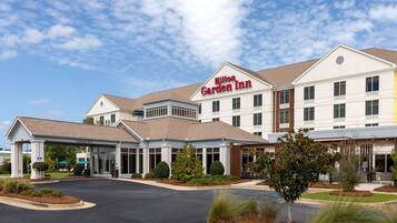 A Hilton Garden Inn with a clear entrance, a covered parking area, and a landscaped front yard.