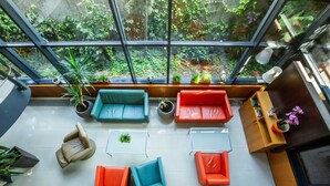 A modern interior with a glass ceiling, multiple seating areas, and a variety of plants. - Impiq Hotel (Trnava)