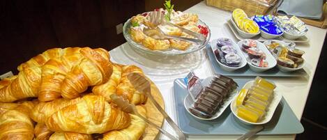 A buffet with various food items including pastries, fruits, and desserts.