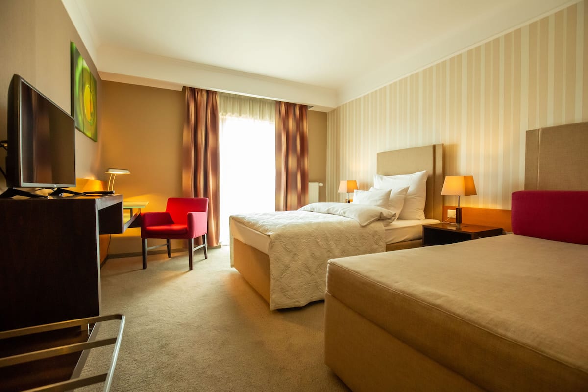 A hotel room with a bed, a desk with a computer, a chair, and a TV.