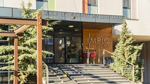 The entrance to IMPIQ Hotel with a staircase leading up to the entrance, surrounded by potted plants and a metal structure. - Impiq Hotel (Trnava)