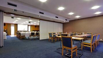 Een vergaderzaal met tafels, stoelen, een projecteerder en een groot scherm.