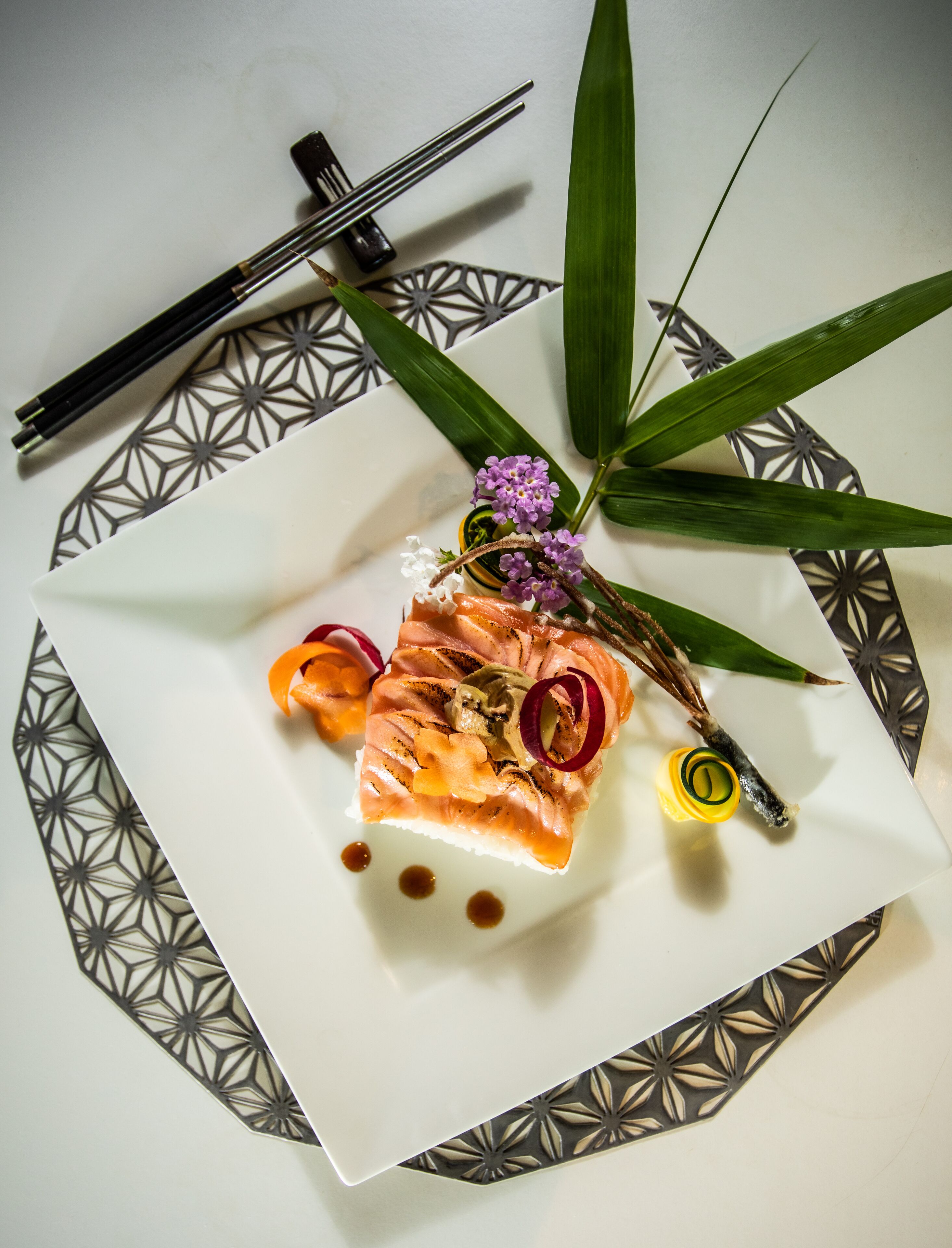 Un plato con salmón, una flor y algunas verduras.