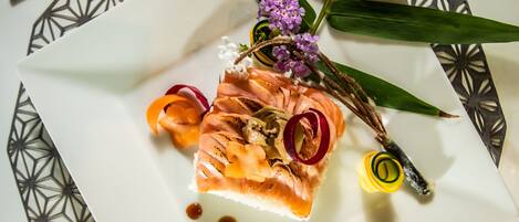 Un plato con salmón, una flor y algunas verduras.
