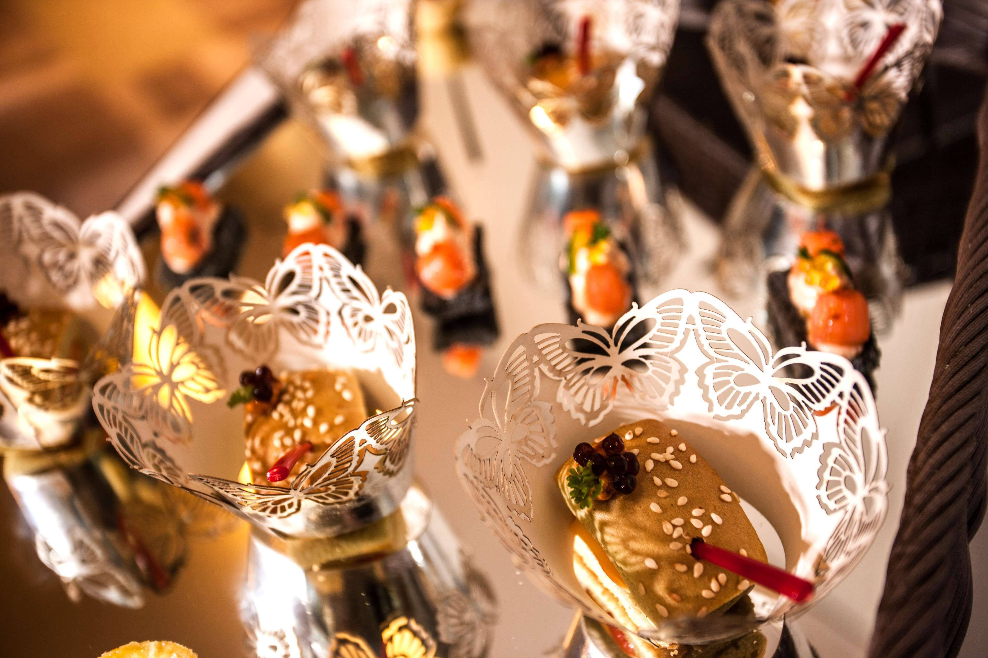 Una mesa con candelabros de cristal que contienen distintos alimentos.