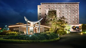 A modern hotel with a prominent entrance, a large conference center, and a tall building in the background. - Hennessy Park Hotel (Ebene)