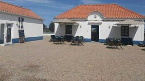 A building with a red-tiled roof and a white facade, featuring a covered patio area with outdoor seating. - Aldeamento Turistico de Palmela (Palmela)