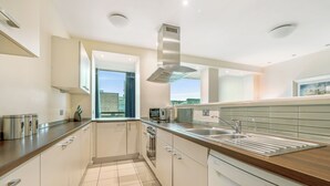 A modern kitchen with white cabinetry, stainless steel appliances, and a wooden countertop. - Princes Street Suites (Edinburgh)