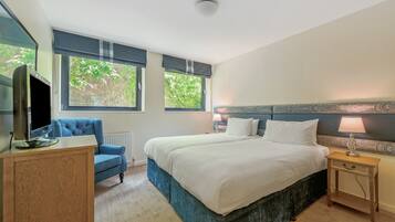 A bedroom with a bed, a desk, a chair, and a TV.