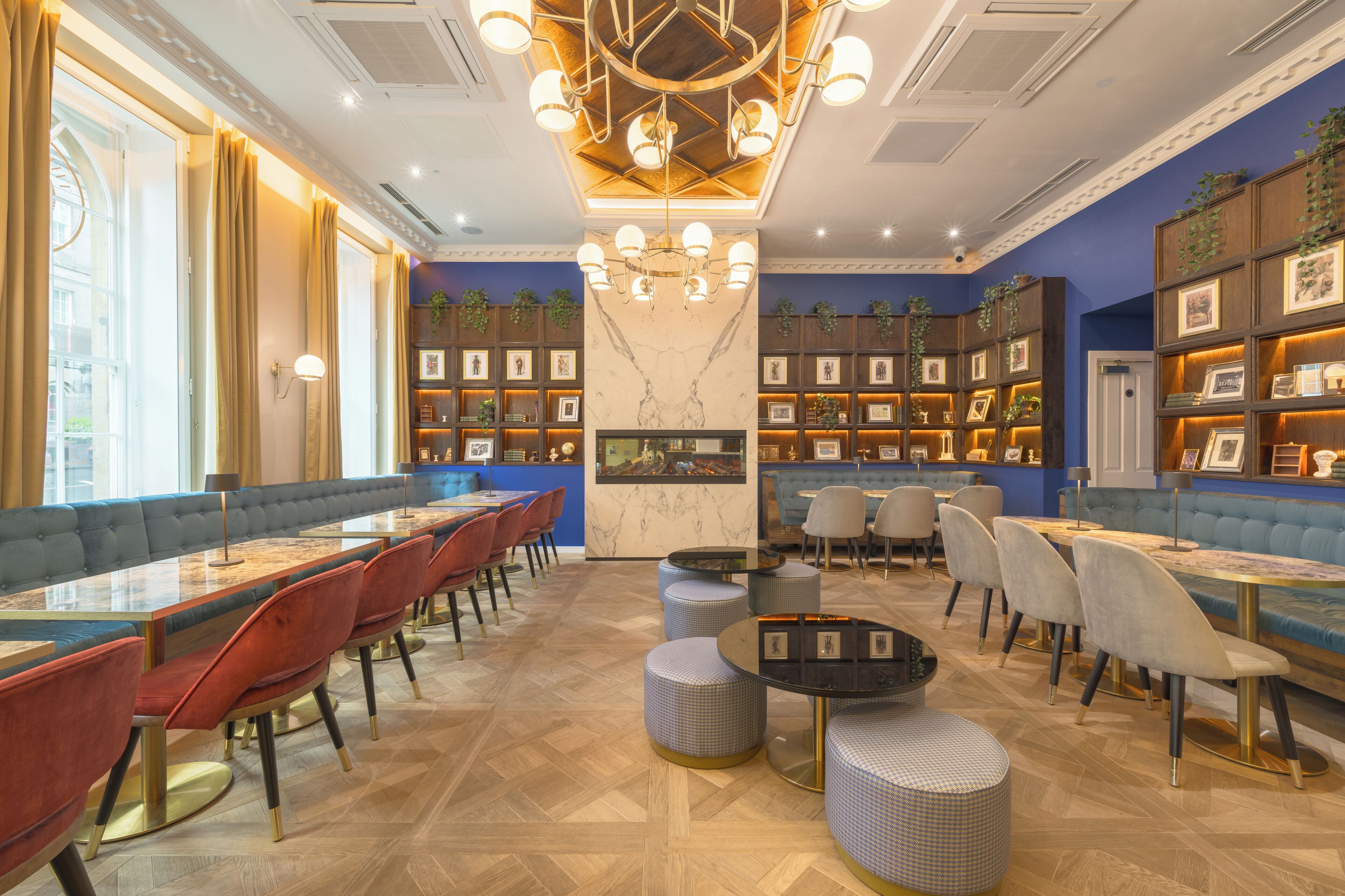 Un restaurante espacioso con techos altos, un candelabro central y diversas opciones de asientos, incluyendo cabinas y mesas.