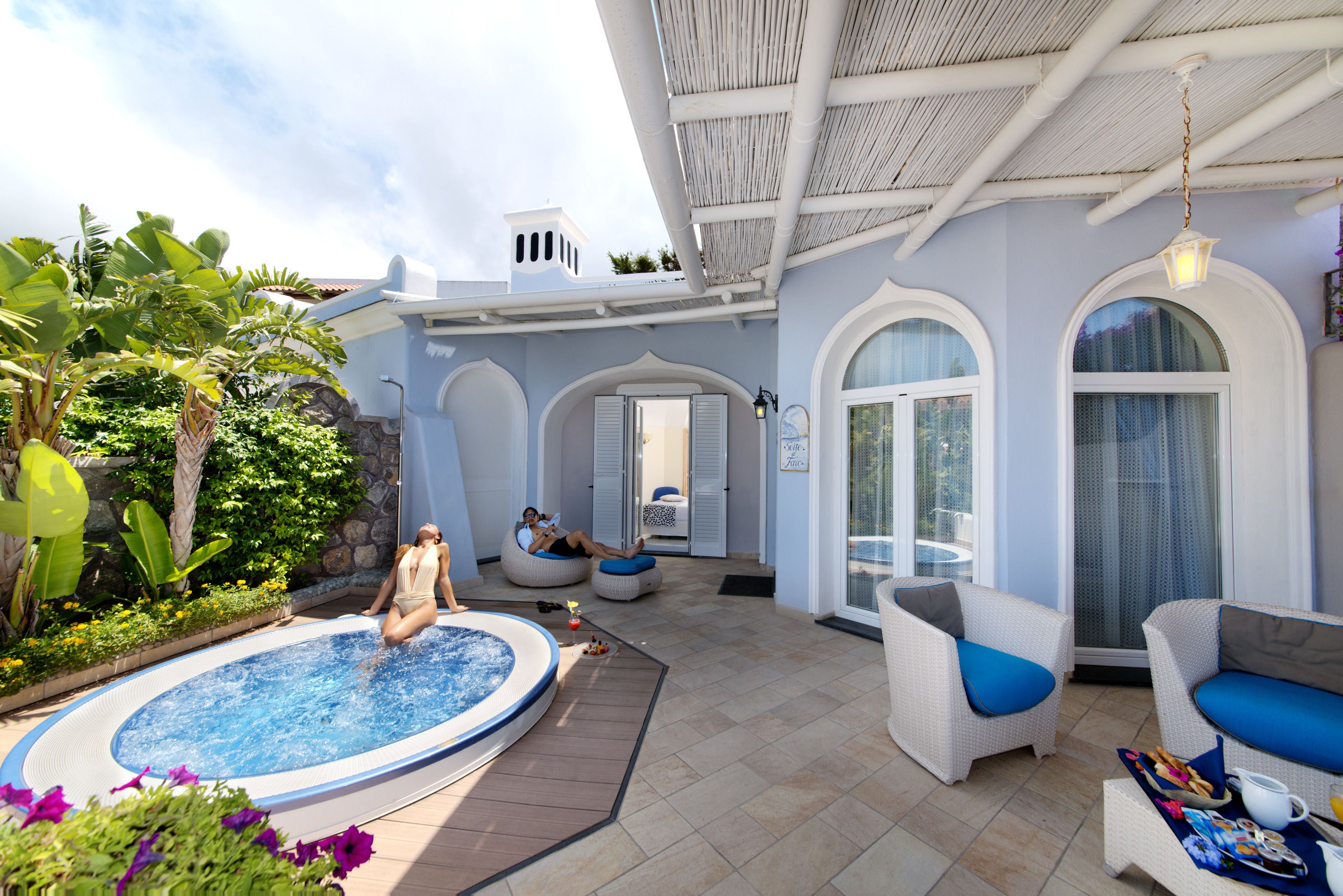 Un espace piscine comprenant un jacuzzi, des chaises longues et un patio couvert agrémenté d’une pergola.