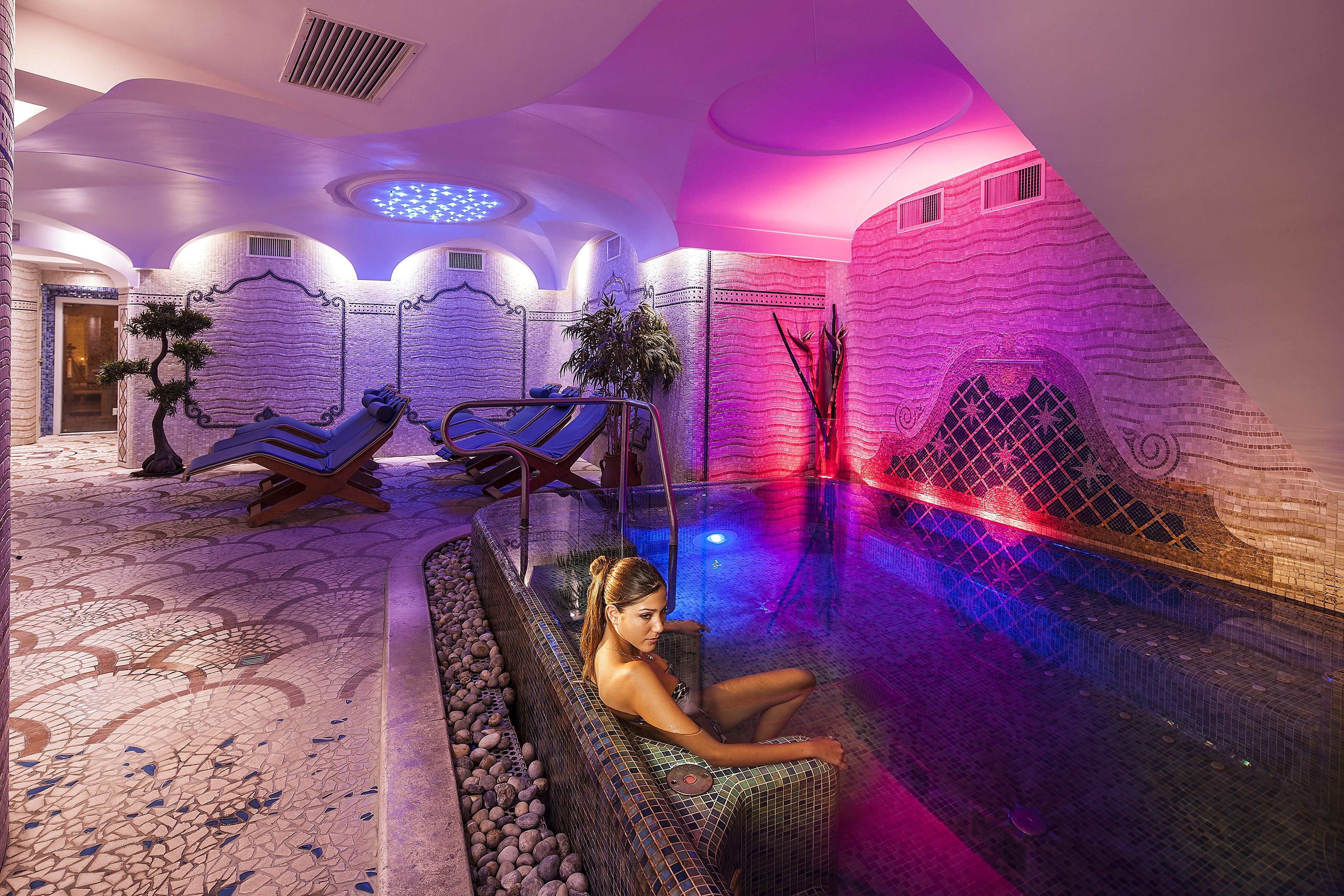 Un área de spa con una bañera de hidromasaje, sillones reclinables y suelo de baldosas.