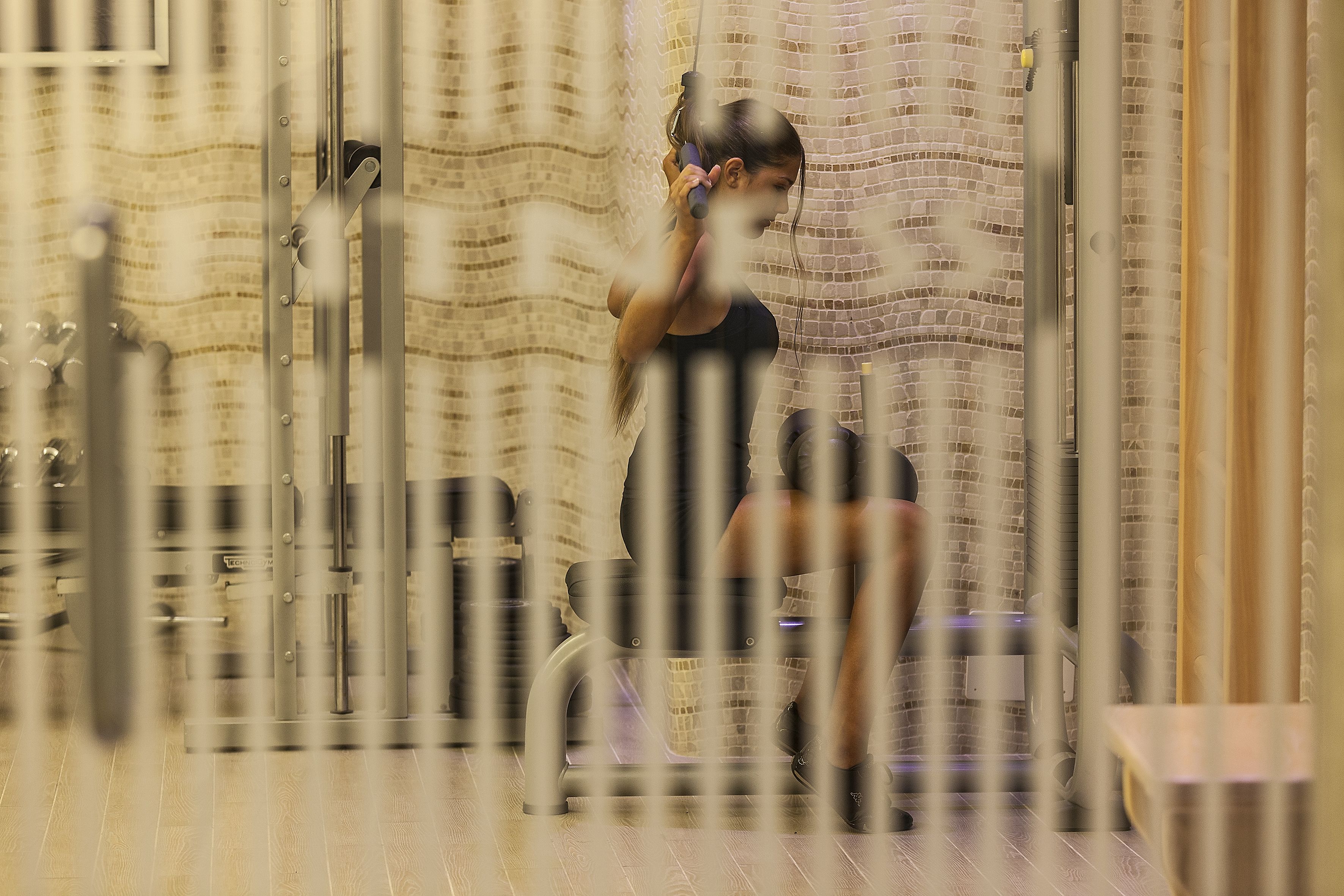 A person using a hairdryer in a room with a brick wall and a wooden floor.