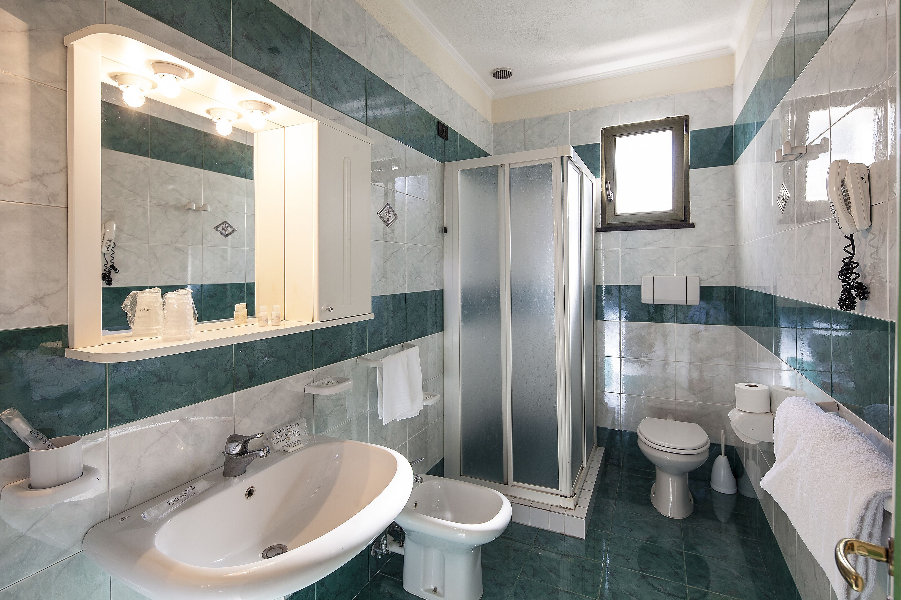 Un bagno moderno con un lavandino capiente, uno specchio e uno spazio doccia.