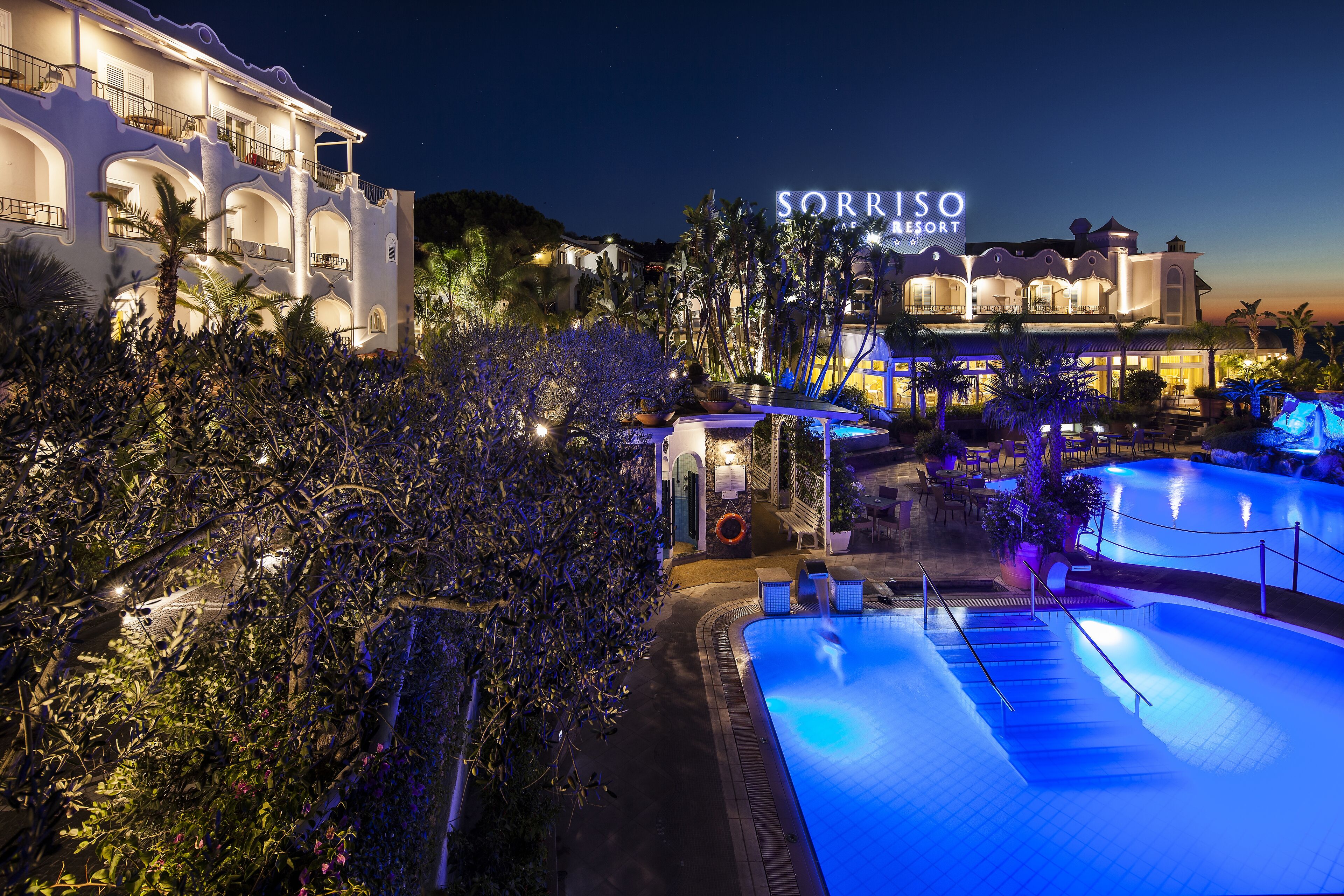 Un resort con piscina, palmeras y un cartel que dice "Sorriso Resort".