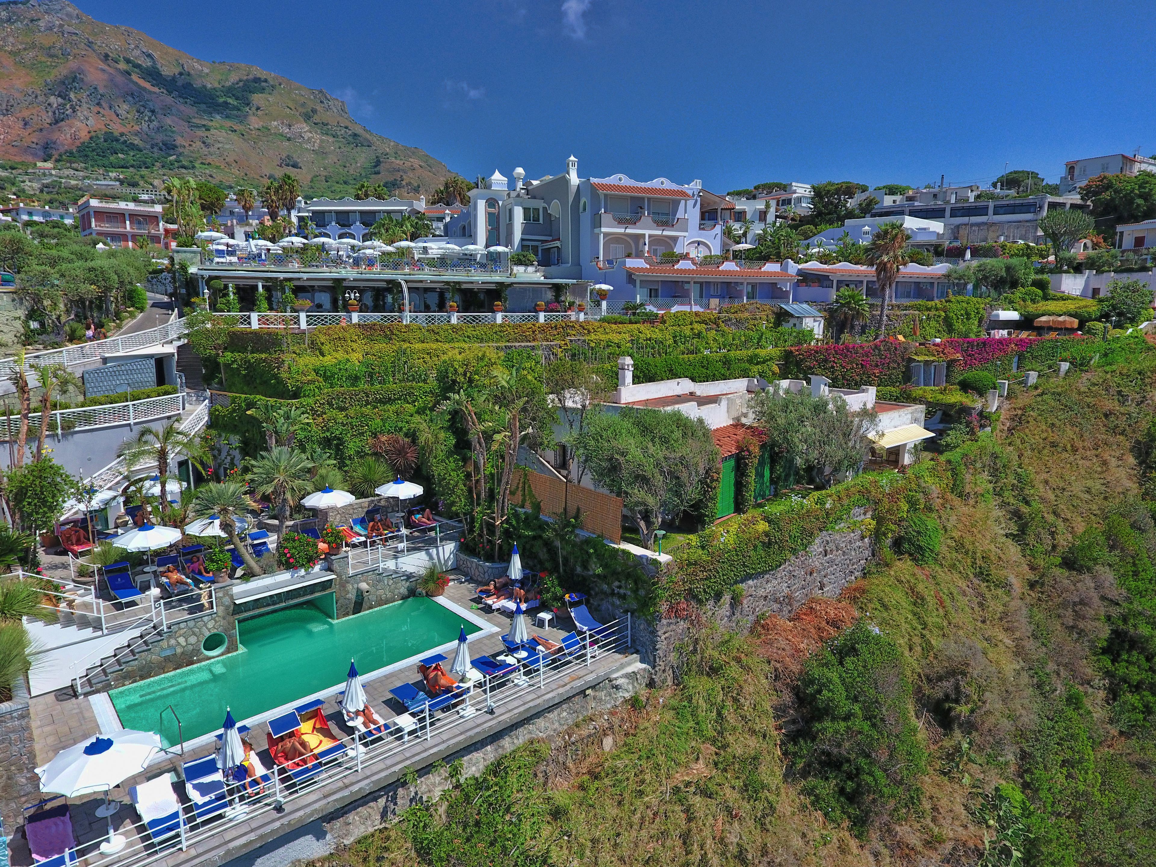 Un complexe hôtelier doté d’une piscine, d’espaces de détente et offrant une vue sur un paysage montagneux.