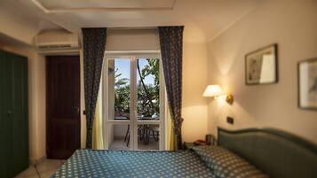 Ein Hotelzimmer mit einem Bett, einem Schreibtisch, einem Stuhl, einem Fenster mit Vorhängen und einer Tür.