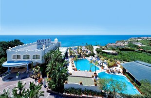 A resort with a large pool, a view of the ocean, and a sign reading "Sorriso Thermae Resort".