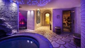 Un área de spa con pared de piedra, una bañera de hidromasaje y un suelo con diseño.